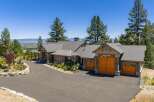 Experience luxury living in this stunning mountain home, featuring a grand entrance with a covered porch and stone accents.