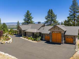 Experience luxury living in this stunning mountain home, featuring a grand entrance with a covered porch and stone accents.