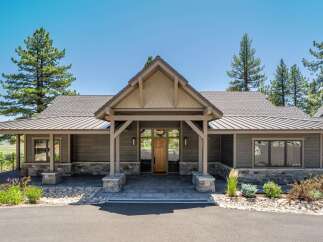 This stunning home features a modern rustic exterior with natural stone accents and dark wood siding.