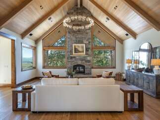 Experience luxury mountain living in this stunning great room, featuring a soaring vaulted wood-beamed ceiling and a magnificent stone fireplace.