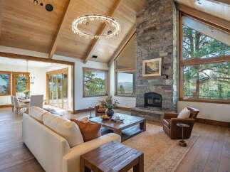 Experience luxury mountain living in this stunning great room featuring a soaring vaulted wood-beamed ceiling and a magnificent floor-to-ceiling stone fireplace.
