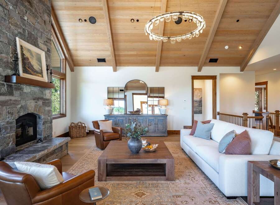 Experience rustic elegance in this stunning living room, featuring a grand stone fireplace and vaulted wood-beamed ceilings.
