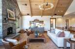 Experience rustic elegance in this stunning living room, featuring a grand stone fireplace and vaulted wood-beamed ceilings.