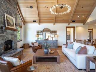 Experience rustic elegance in this stunning living room, featuring a grand stone fireplace and vaulted wood-beamed ceilings.