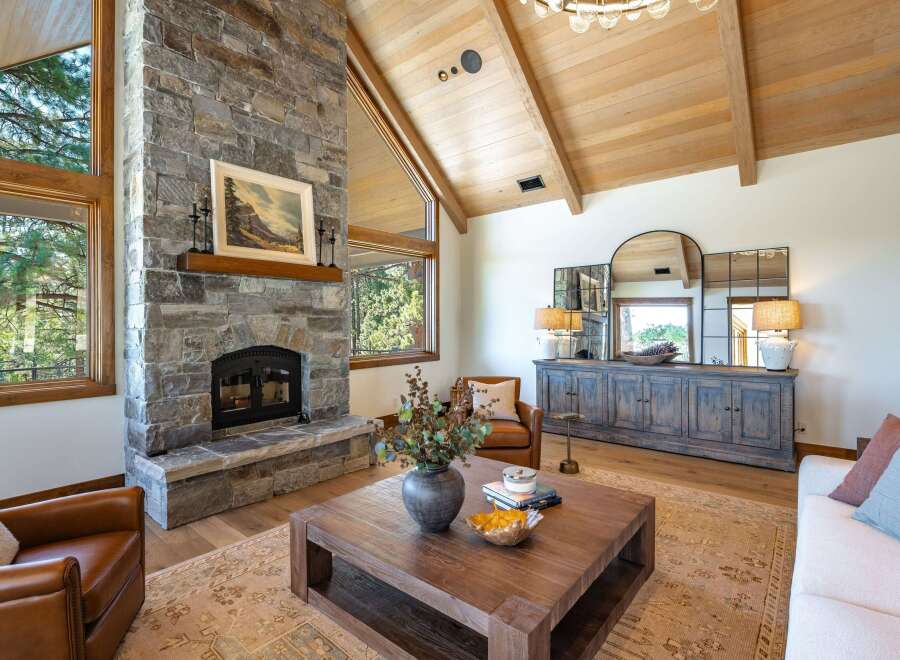 Experience rustic elegance in this stunning living room, featuring a grand stone fireplace and vaulted wood-beamed ceilings.