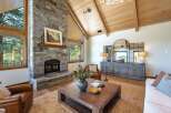 Experience rustic elegance in this stunning living room, featuring a grand stone fireplace and vaulted wood-beamed ceilings.