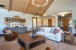 Experience luxurious living in this stunning great room, featuring a vaulted wood-beamed ceiling and a modern circular chandelier.