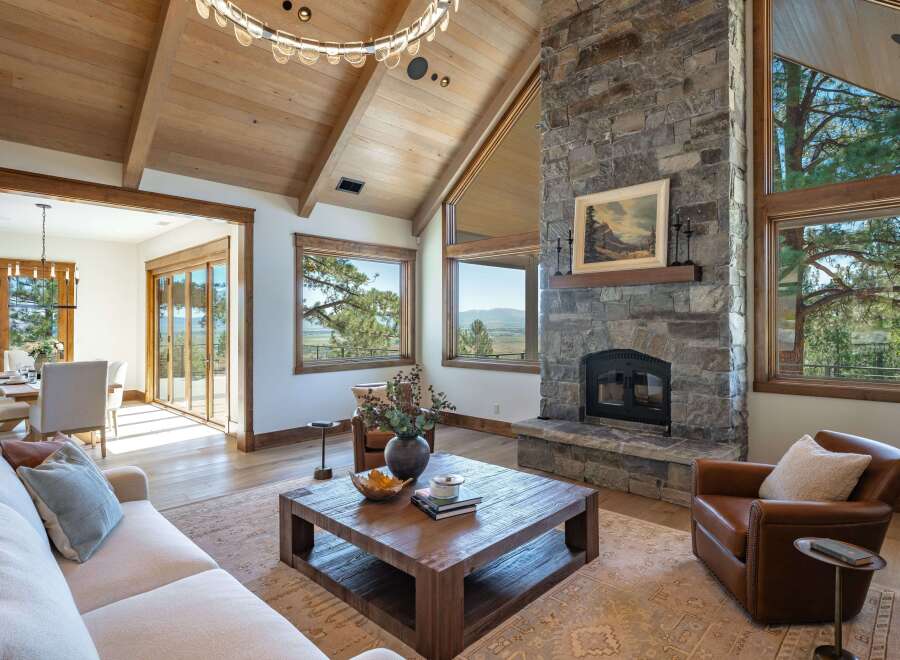 Experience luxury mountain living in this stunning great room, featuring a grand stone fireplace and vaulted wood-beamed ceilings.
