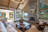 Experience luxury mountain living in this stunning great room, featuring a grand stone fireplace and vaulted wood-beamed ceilings.