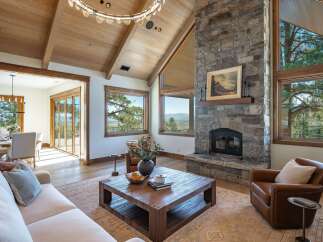 Experience luxury mountain living in this stunning great room, featuring a grand stone fireplace and vaulted wood-beamed ceilings.