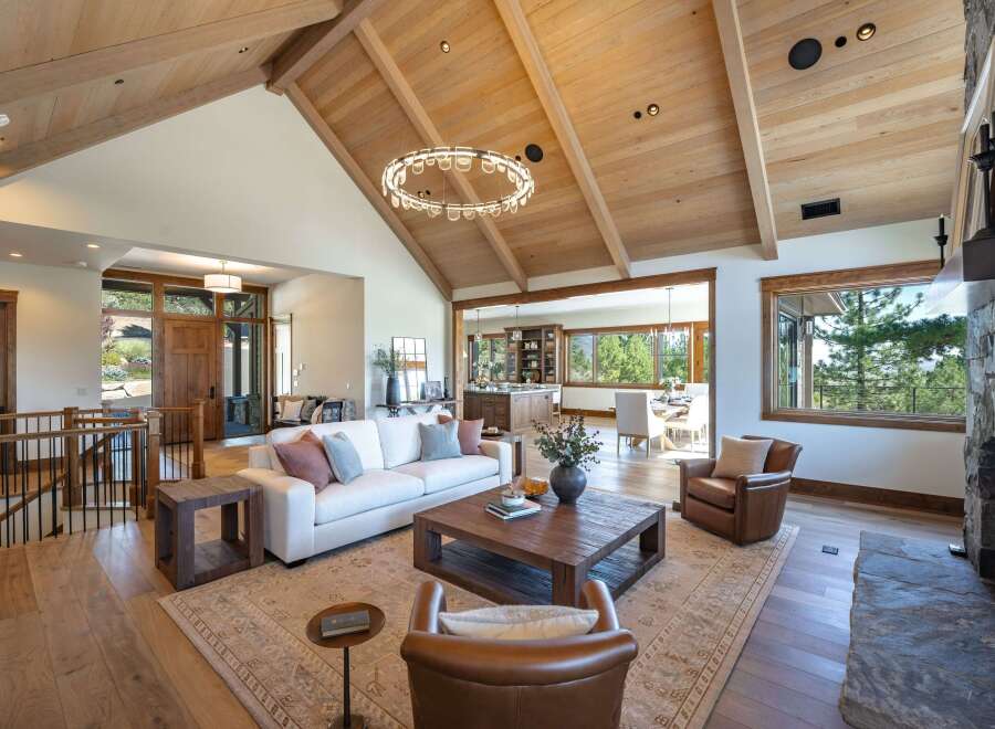 Experience luxurious mountain living in this stunning great room, featuring a vaulted wood-beamed ceiling and a modern circular chandelier.