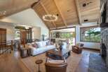Experience luxurious mountain living in this stunning great room, featuring a vaulted wood-beamed ceiling and a modern circular chandelier.