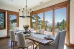 Experience breathtaking mountain views from this elegant dining room, featuring a large wooden table set for six and a modern chandelier.
