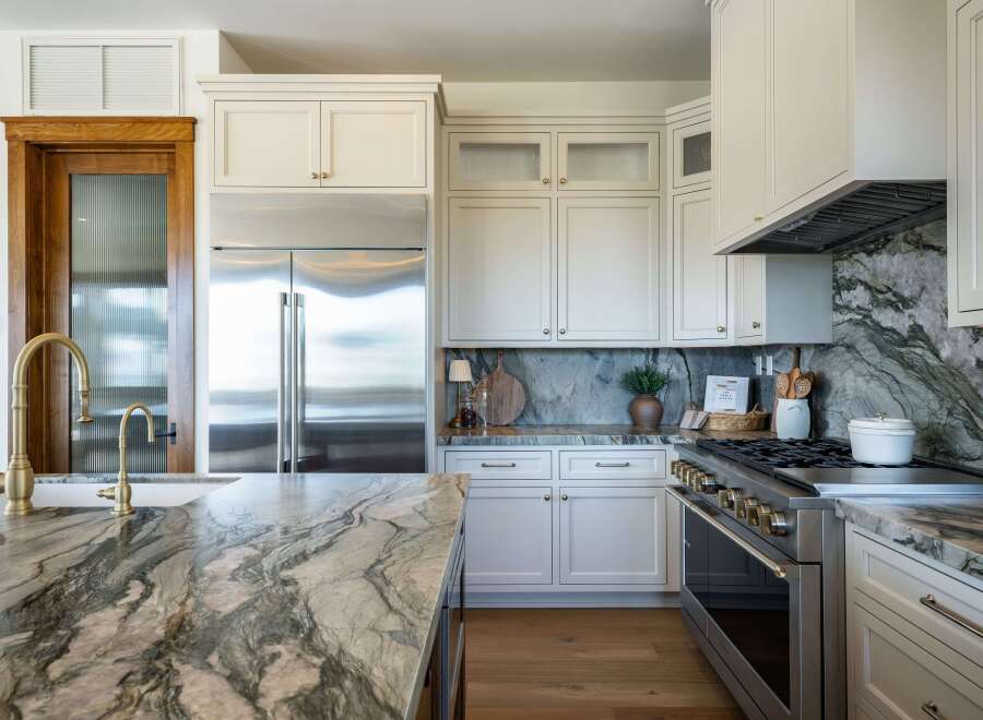 Experience luxury in this stunning kitchen, featuring a large island with a dramatic marble countertop and a matching backsplash.