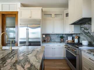 Experience luxury in this stunning kitchen, featuring a large island with a dramatic marble countertop and a matching backsplash.
