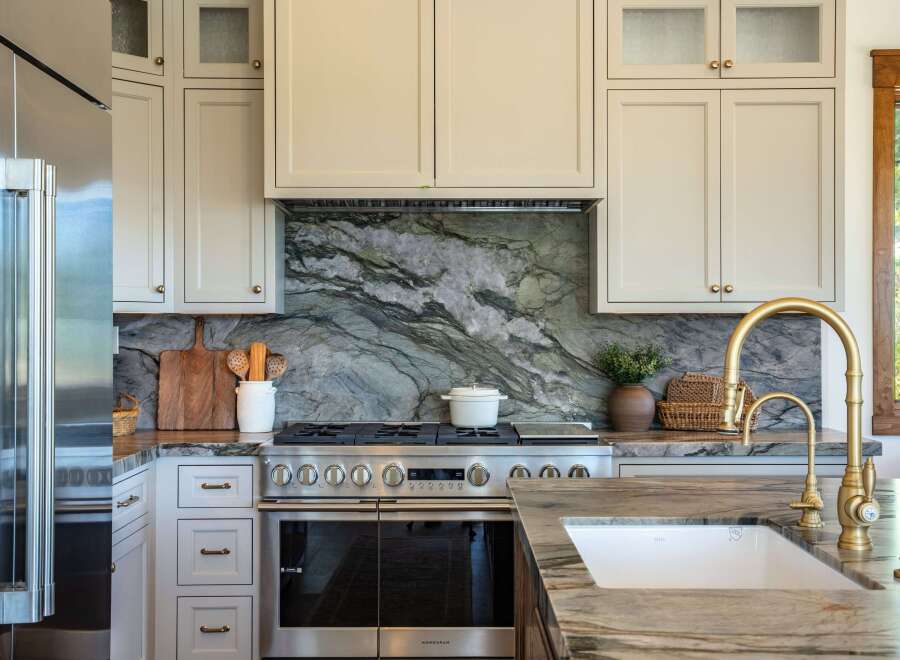 Experience luxury in this stunning kitchen, featuring a dramatic green marble backsplash that perfectly complements the custom cabinetry and high-end stainless steel appliances.