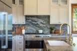 Experience luxury in this stunning kitchen, featuring a dramatic green marble backsplash that perfectly complements the custom cabinetry and high-end stainless steel appliances.