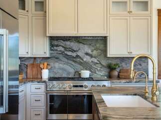 Experience luxury in this stunning kitchen, featuring a dramatic green marble backsplash that perfectly complements the custom cabinetry and high-end stainless steel appliances.