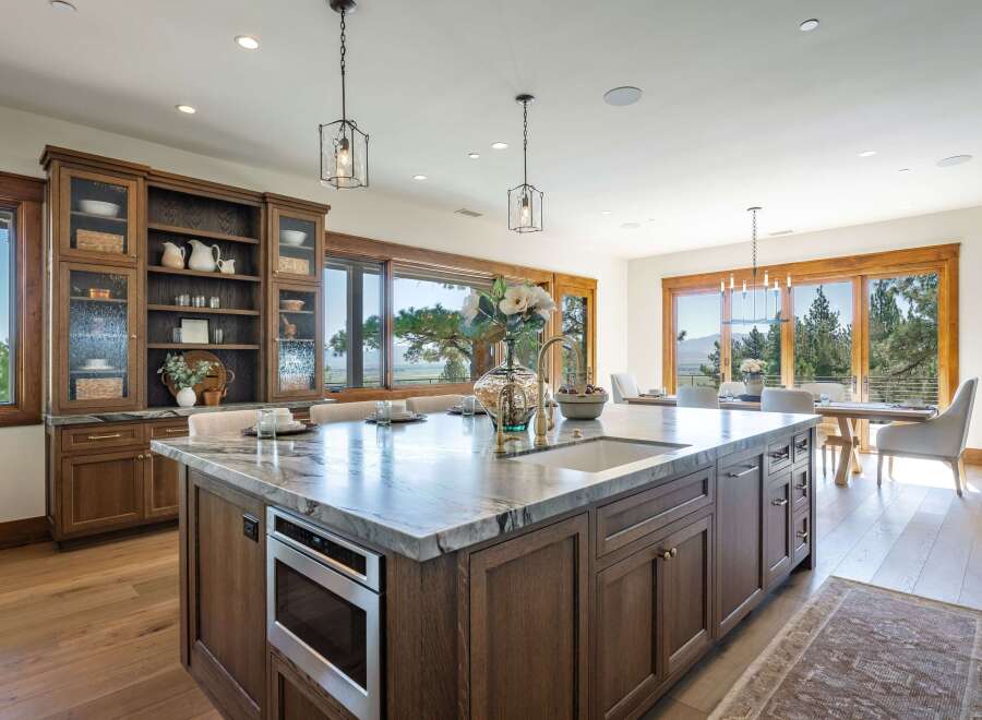 Experience luxury living in this stunning kitchen featuring a large marble island with a built-in microwave and sink, complemented by custom wood cabinetry.