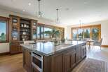 Experience luxury living in this stunning kitchen featuring a large marble island with a built-in microwave and sink, complemented by custom wood cabinetry.