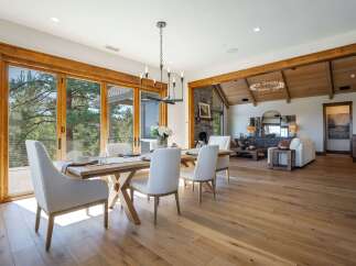 Experience luxurious open-concept living with this stunning dining and living area, featuring expansive sliding glass doors that open to breathtaking natural views.