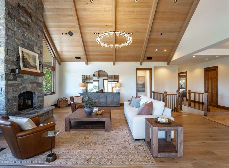 Experience luxurious mountain living in this stunning great room, featuring a soaring vaulted wood-beamed ceiling and a magnificent floor-to-ceiling stone fireplace.