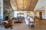 Experience luxurious mountain living in this stunning great room, featuring a soaring vaulted wood-beamed ceiling and a magnificent floor-to-ceiling stone fireplace.