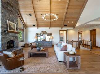 Experience luxurious mountain living in this stunning great room, featuring a soaring vaulted wood-beamed ceiling and a magnificent floor-to-ceiling stone fireplace.