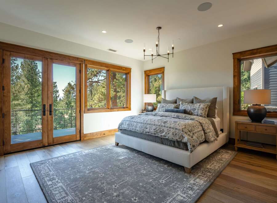 Experience luxurious mountain living in this stunning bedroom featuring a king-sized bed with a plush upholstered headboard and a beautiful floral duvet.