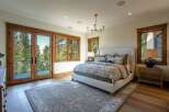 Experience luxurious mountain living in this stunning bedroom featuring a king-sized bed with a plush upholstered headboard and a beautiful floral duvet.