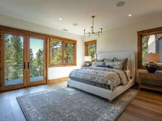 Experience luxurious mountain living in this stunning bedroom featuring a king-sized bed with a plush upholstered headboard and a beautiful floral duvet.