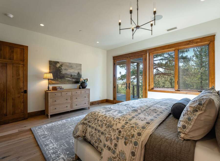 Experience luxury living in this stunning bedroom featuring a large wooden dresser adorned with a beautiful landscape painting and a table lamp.