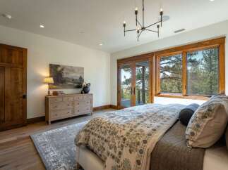 Experience luxury living in this stunning bedroom featuring a large wooden dresser adorned with a beautiful landscape painting and a table lamp.