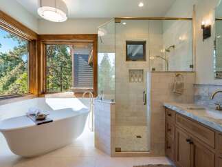 Experience luxury in this stunning bathroom featuring a freestanding soaking tub with a picturesque view of the surrounding forest.