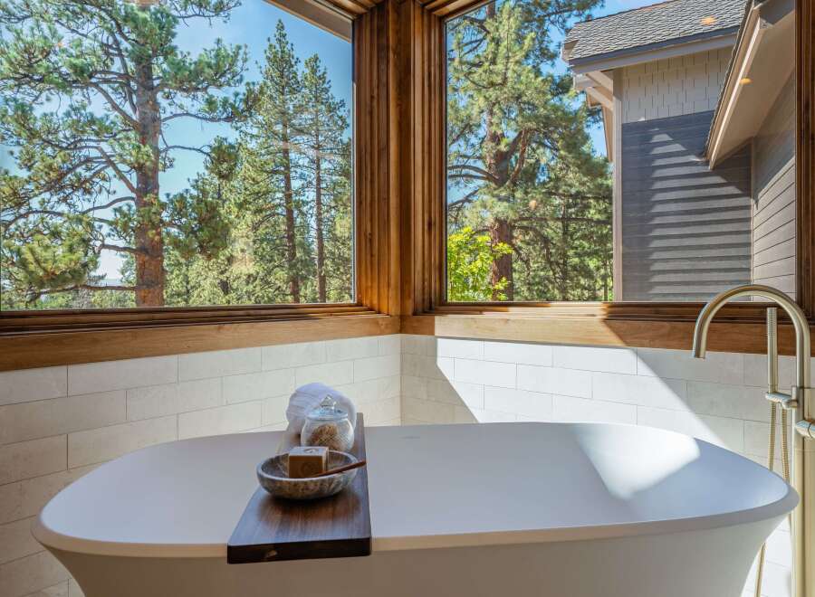 Indulge in ultimate relaxation in this luxurious bathroom, featuring a stunning freestanding bathtub with a breathtaking view of the surrounding pine forest.