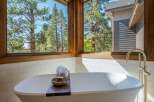 Indulge in ultimate relaxation in this luxurious bathroom, featuring a stunning freestanding bathtub with a breathtaking view of the surrounding pine forest.
