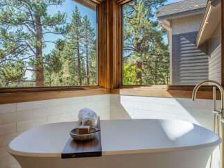 Indulge in ultimate relaxation in this luxurious bathroom, featuring a stunning freestanding bathtub with a breathtaking view of the surrounding pine forest.