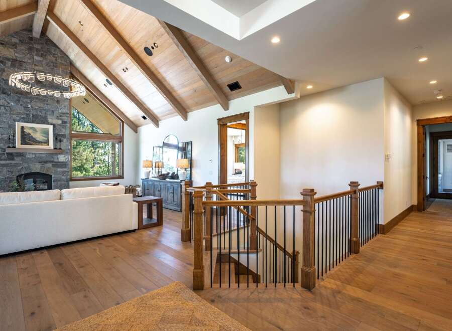 Experience luxury living in this stunning home featuring a grand living area with a soaring stone fireplace and vaulted wood-beamed ceilings.