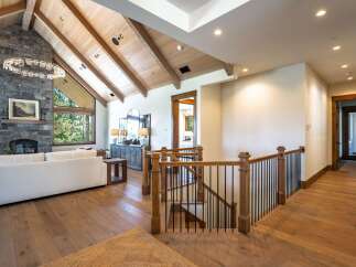 Experience luxury living in this stunning home featuring a grand living area with a soaring stone fireplace and vaulted wood-beamed ceilings.