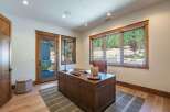 This home office features a large wooden desk with a leather chair, complemented by a stylish plaid rug and a comfortable ottoman.