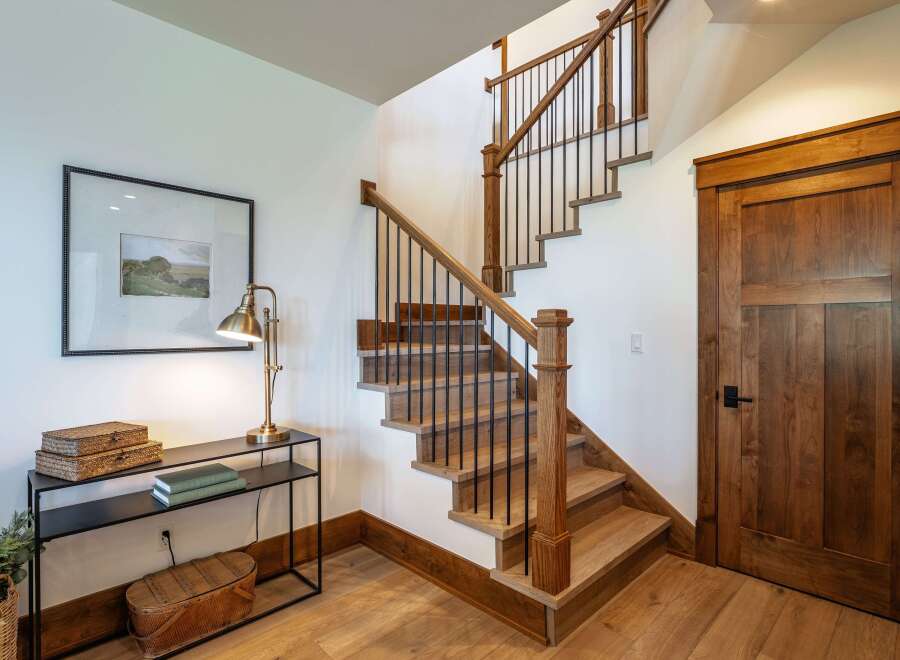 Ascend to the upper level via this beautifully crafted wooden staircase, featuring a sleek black metal railing and sturdy oak treads.