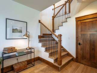 Ascend to the upper level via this beautifully crafted wooden staircase, featuring a sleek black metal railing and sturdy oak treads.