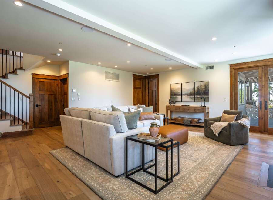 Experience luxurious living in this spacious great room, featuring a comfortable sectional sofa, a stylish accent chair, and a large area rug.