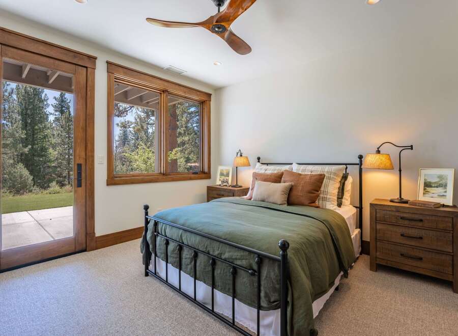 Experience rustic charm in this inviting bedroom, featuring a cozy queen-size bed dressed in a deep green duvet and accented with plush throw pillows.