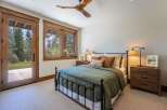 Experience rustic charm in this inviting bedroom, featuring a cozy queen-size bed dressed in a deep green duvet and accented with plush throw pillows.