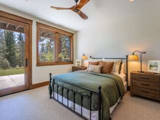 Experience rustic charm in this inviting bedroom, featuring a cozy queen-size bed dressed in a deep green duvet and accented with plush throw pillows.