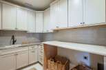 Discover this beautifully appointed laundry room featuring pristine white cabinetry and elegant subway tile backsplash.