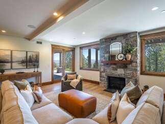 Experience luxury living in this stunning mountain retreat, featuring a grand stone fireplace and expansive windows that frame breathtaking natural views.