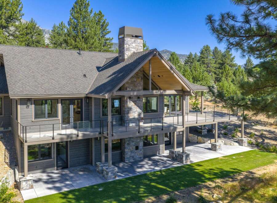 Experience luxury mountain living in this stunning custom-built home, featuring a striking stone chimney and expansive wrap-around deck perfect for enjoying the breathtaking natural surroundings.