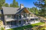 Experience luxury mountain living in this stunning custom-built home, featuring a striking stone chimney and expansive wrap-around deck perfect for enjoying the breathtaking natural surroundings.